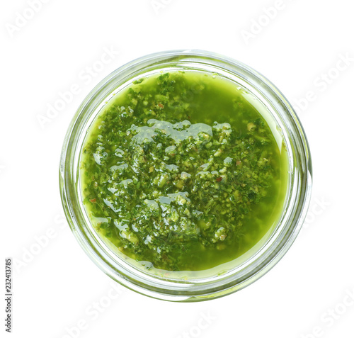 Homemade basil pesto sauce in glass jar on white background, top view