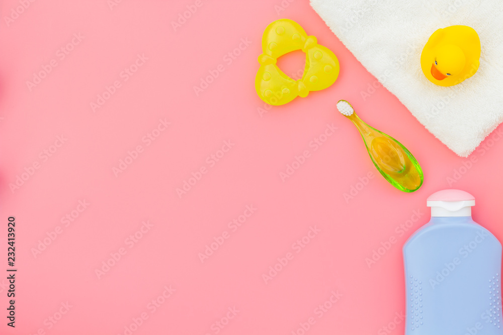 Baby care. Bath cosmetics and accessories for child with towel and yellow rubber duck on pink background top view copy space Baby care. Bath cosmetics and accessories for child with towel and yellow rubber duck on pink background top view copy space