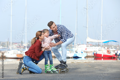 Happy family wearing roller skates on embankment