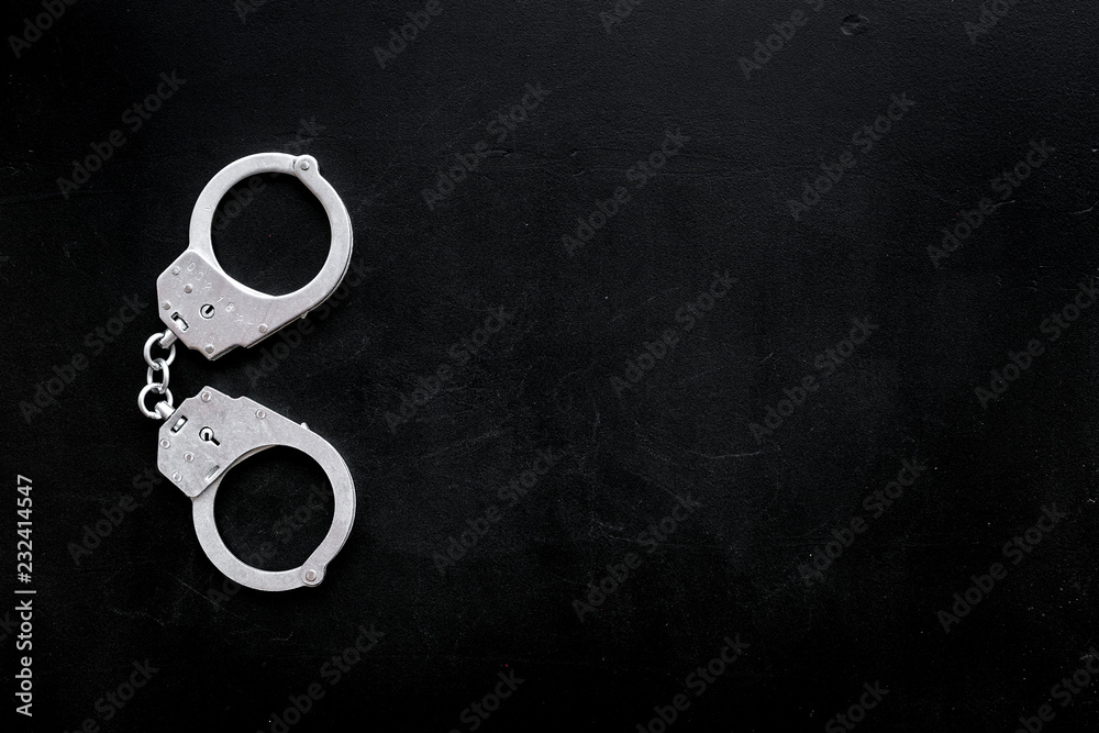 Metal handcuffs on black background top view space for text Metal handcuffs on black background top view space for text