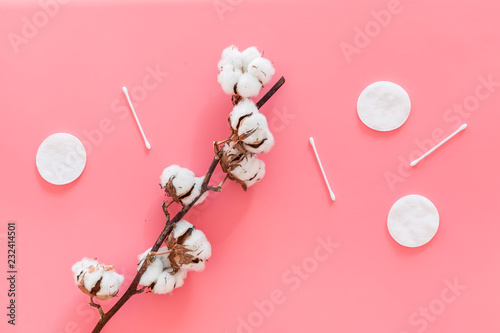 Bath accessories. Products for remove cosmetics. Cotton swabs and cotton pads near dry cotton flowers on pink background top view