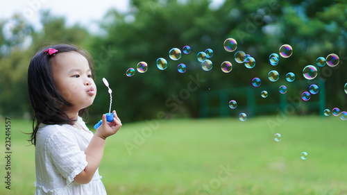 Canvas-taulu Asian cute little girl blowing to make many bubbles in public garden at holiday or vacation