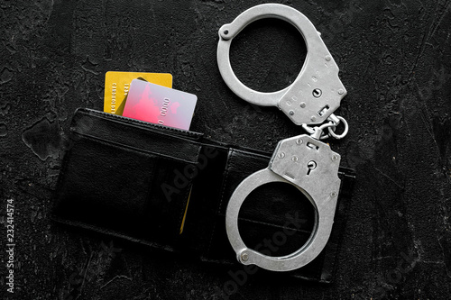 Arrest of cybercriminals, hackers concept. Handcuff near bank card on black background top view space for text photo