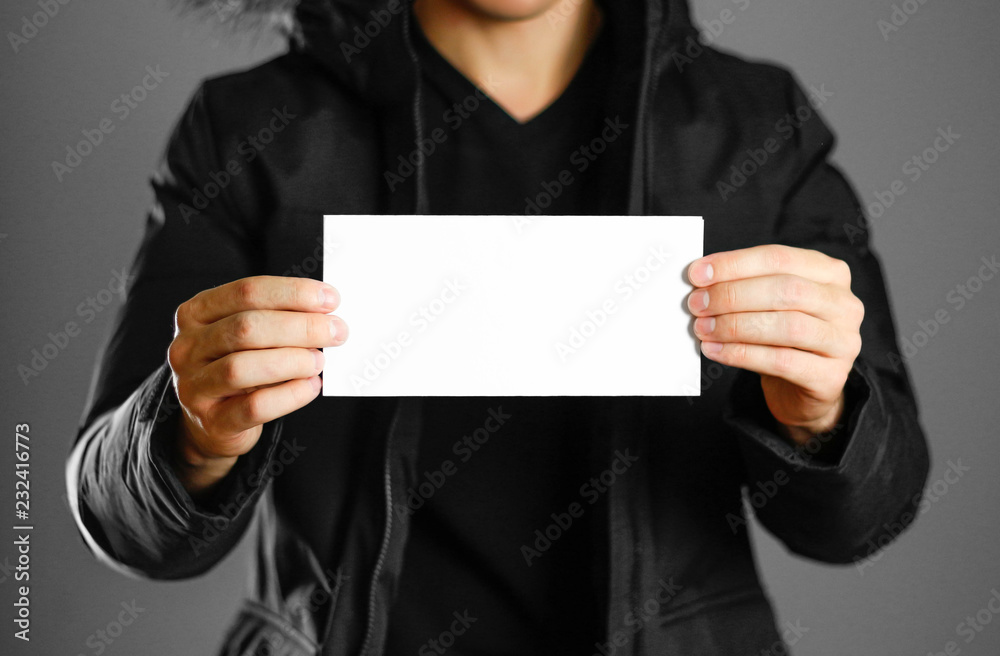 A man in a warm winter jacket holding a white leaflet. Blank paper. Close up. Isolated background A man in a warm winter jacket holding a white leaflet. Blank paper. Close up. Isolated background