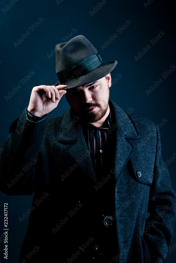portrait of a man in a black hat and coat on a dark background, Studio photo portrait of a man in a black hat and coat on a dark background, Studio photo