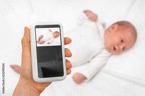 Mother is holding baby monitor camera for safety of her baby