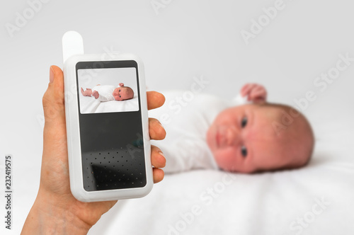 Mother is holding baby monitor camera for safety of her baby