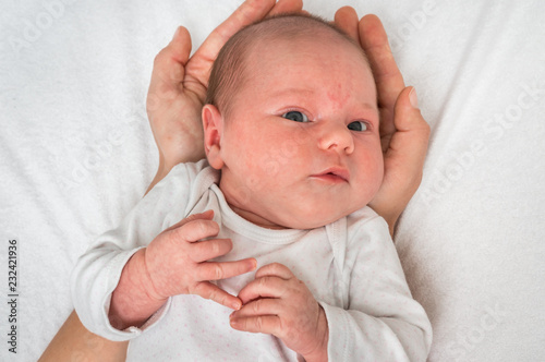 One month old newborn baby is lying on hands of mother