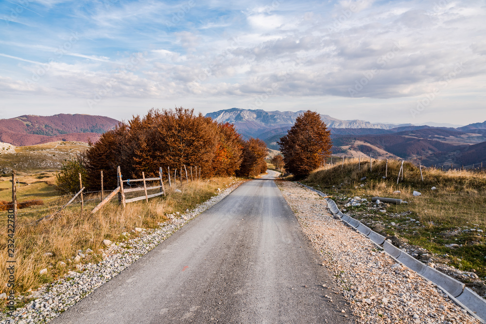 Empty asphalt road with autumnal trees and mountains in Bosnia