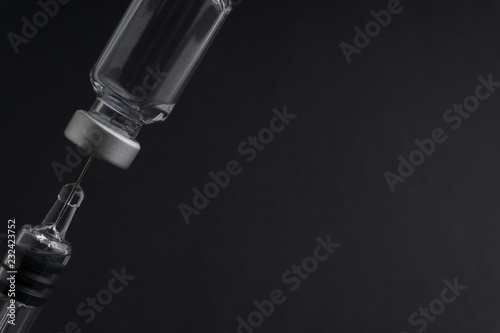 Medical syringe and vial on dark background with selective focus and crop fragment