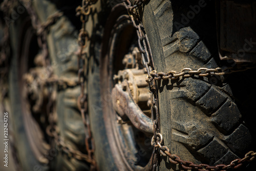 Large wheels of an old ZIL military car with smooth rubber and anti-slip chains. Huge wheels of a retro car close up photo