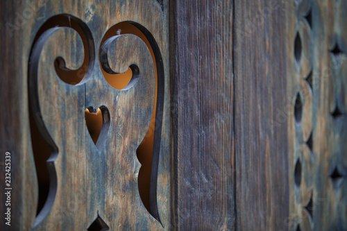 Brown wooden carved vintage shutters on the Windows of the house in Georgia. Picturesque streets of Borjomi. Yellow light is visible from the slot of shutters