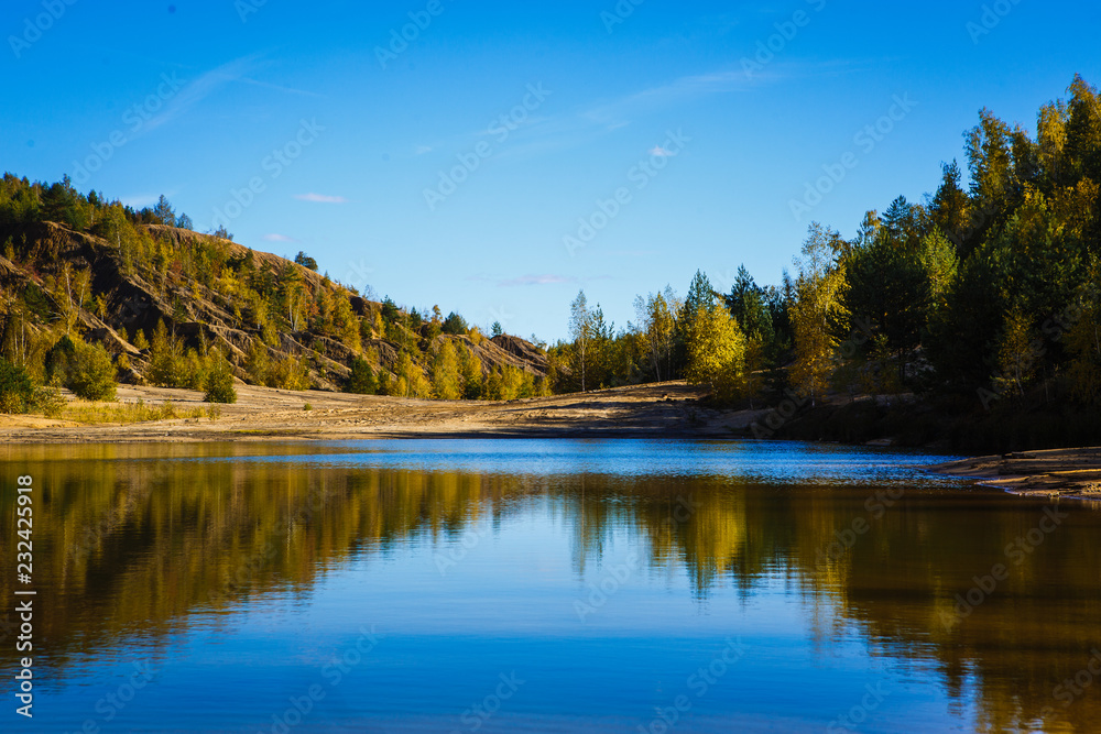 Blue lake on a bright Sunny day, the reflection of sandy shores in the water. Wide river valley in a mountainous area