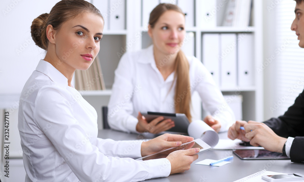 Group of business people at meeting on the background of office. Focus at a beautiful brunette woman Group of business people at meeting on the background of office. Focus at a beautiful brunette woman