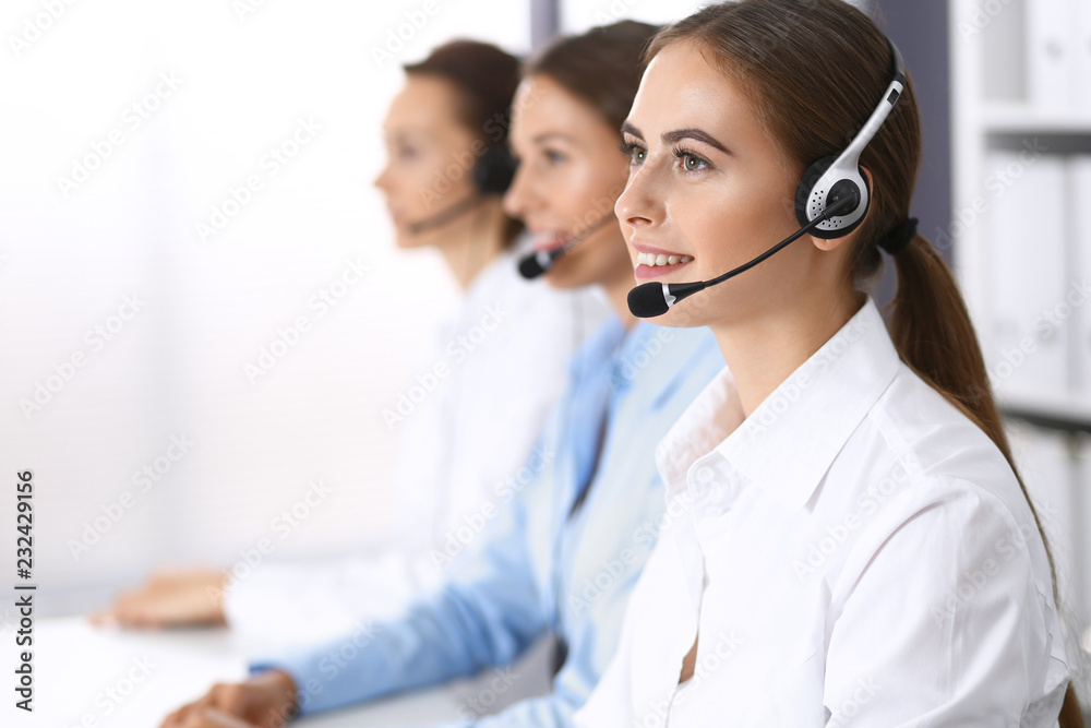 Call center. Group of operators at work. Focus on beautiful business woman in headset Call center. Group of operators at work. Focus on beautiful business woman in headset