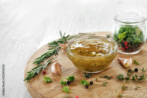 Tasty sauce in bowl with herbs and spices on wooden board