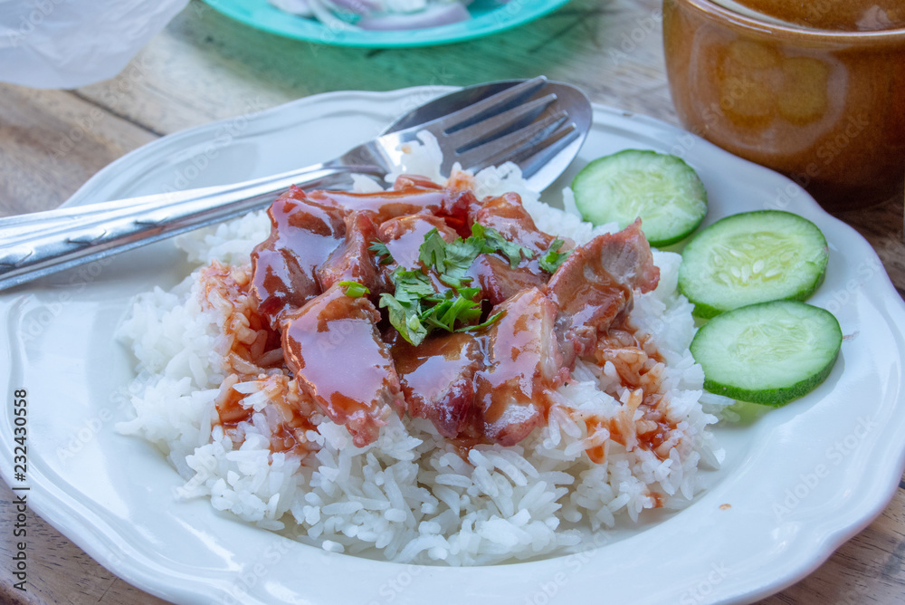 Red pork with rice and cucumber on a plate.