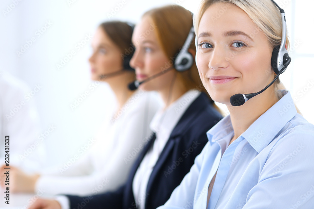 Call center. Group of operators at work. Focus at blonde business woman in headset Call center. Group of operators at work. Focus at blonde business woman in headset