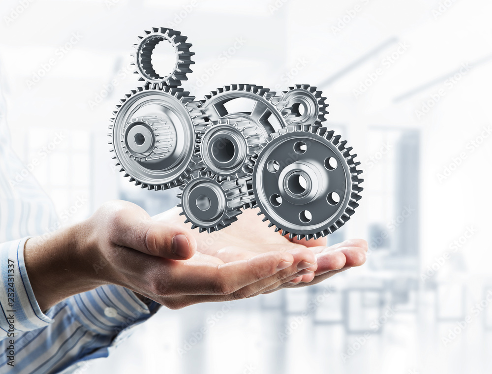 Engine mechanism in male ahnds as symbol for cooperation or team Engine mechanism in male ahnds as symbol for cooperation or team