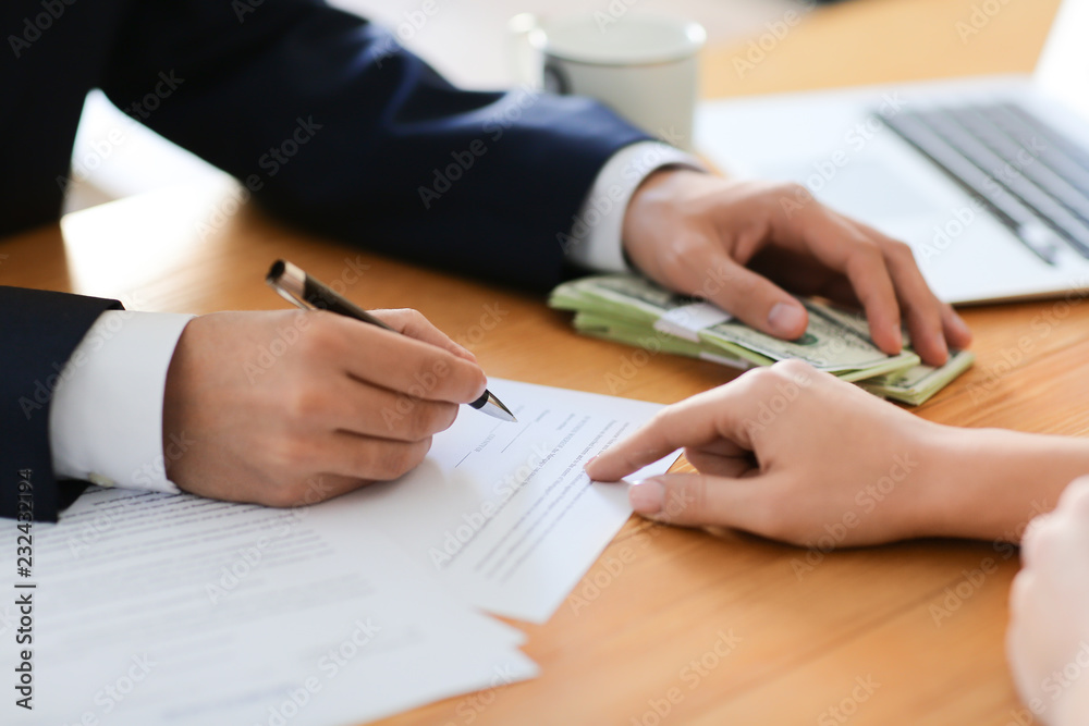 Businessman with bribe signing contract at table, closeup. Corruption concept Businessman with bribe signing contract at table, closeup. Corruption concept