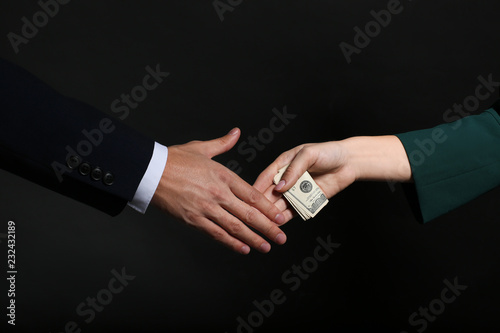 Businessman taking bribe from woman on dark background. Corruption concept