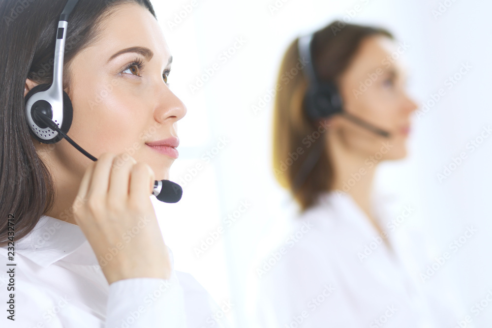Group of call center operators at work. Focus on beautiful business woman in headset Group of call center operators at work. Focus on beautiful business woman in headset