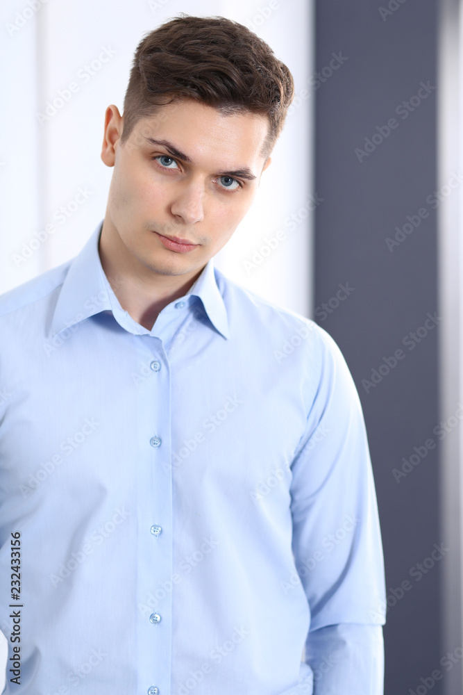 Young businessman standing straight in office. Business concept Young businessman standing straight in office. Business concept