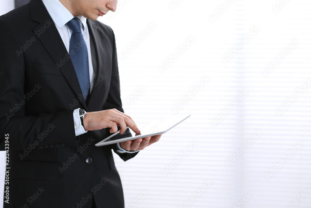 Unknown businessman holding digital tablet in office Unknown businessman holding digital tablet in office
