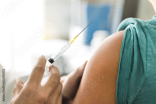 Vaccine or flu shot in injection needle. Doctor working with patient s arm. Physician or nurse giving vaccination and immunity to virus  influenza or HPV with syringe. Appointment with medical expert.