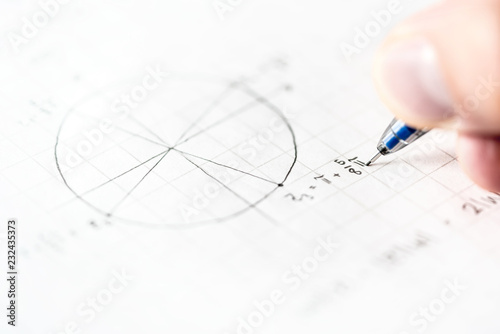 Student doing math homework or mathematics test in school class. Writing mathematical equation and numbers for geometry assignment on paper with pen. Notes during lesson and teaching. Schoolwork.