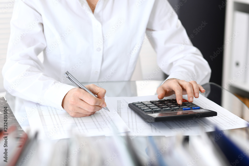 Bookkeeper woman or financial inspector making report, calculating or checking balance, close-up. Business portrait. Copy space area for audit or tax concepts Bookkeeper woman or financial inspector making report, calculating or checking balance, close-up. Business portrait. Copy space area for audit or tax concepts