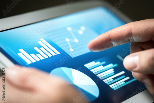 Statistics, graphs, trends and growth on tablet screen. Financial management and development with technology in business. Businessman using monitor to analyze market performance and figures. photo