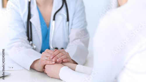 Medicine doctor hand reassuring her female patient closeup. Medicine, comforting and trusting concept in health care