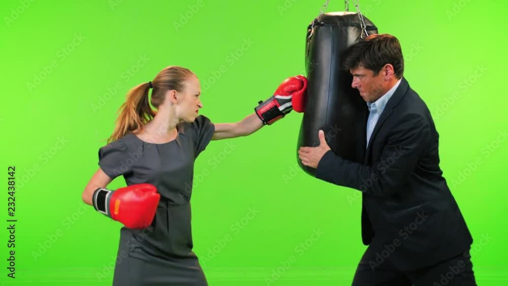 Slow Motion Frustrated Businesswoman trains while a businessman holds her bag over a green screen. Slow Motion Frustrated Businesswoman trains while a businessman holds her bag over a green screen.