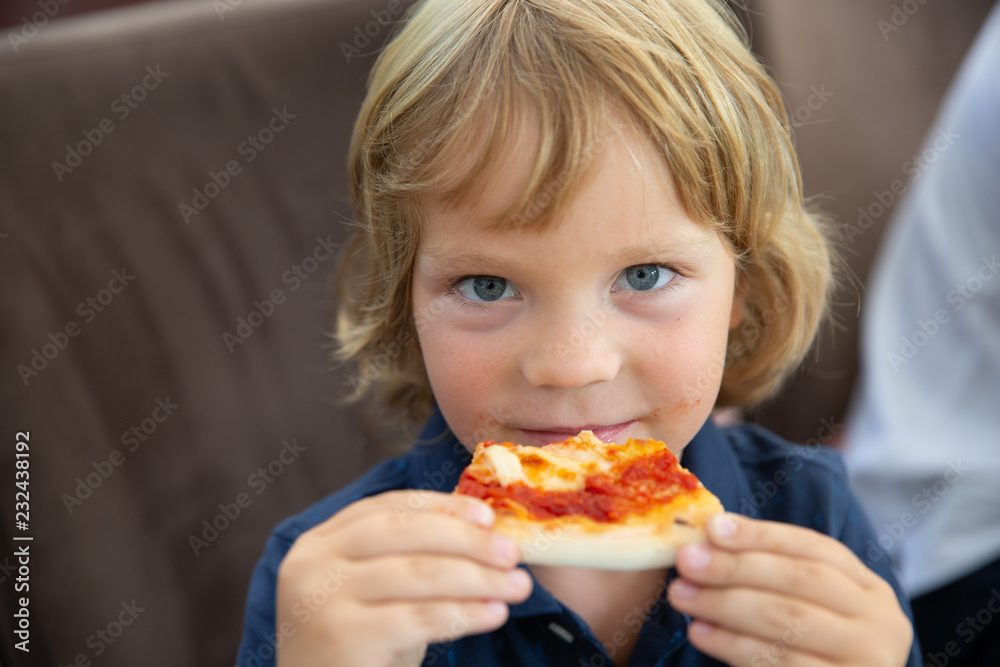 The boy is eating pizza in an Italian restaurant