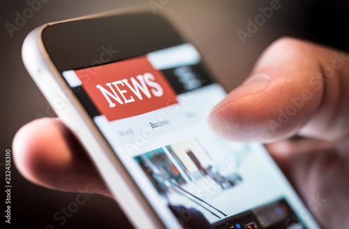 Online news in mobile phone. Close up of smartphone screen. Man reading articles in application. Hand holding smart device. Mockup website. Newspaper and portal on internet. photo