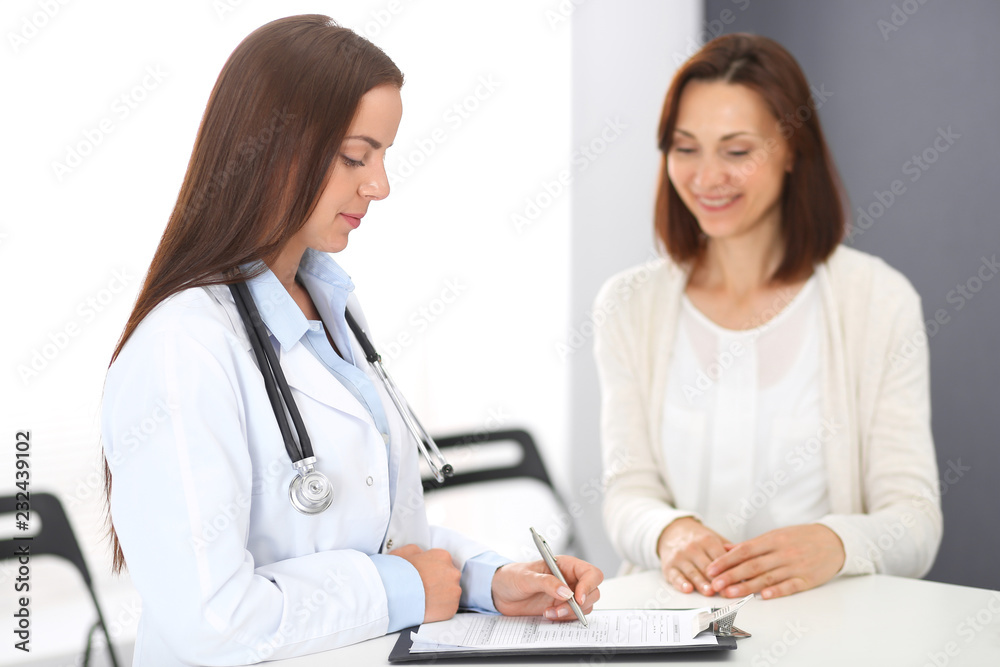 Doctor and patient discussing something while standing near reception desk in emergency hospital. Physician at work in clinic. Medicine and health care concept Doctor and patient discussing something while standing near reception desk in emergency hospital. Physician at work in clinic. Medicine and health care concept