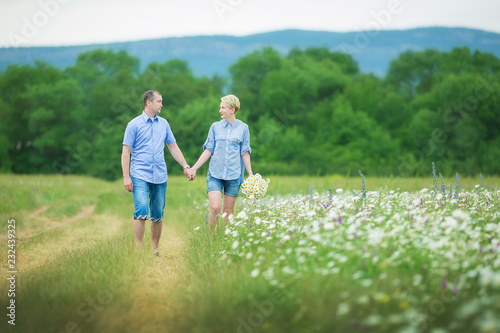 Romantic couple hugging and breathing fresh air in a warm field with daizy flowers