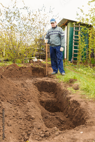 A young man in the country plot prepares the land for planting seedlings. photo