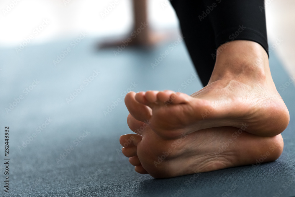 Young sporty woman practicing yoga, doing strengthening exercises, healing  physical therapy pose, working out, indoor close up, yoga studio, focus on  feet. Foot and heel care, fitness concept Stock Photo