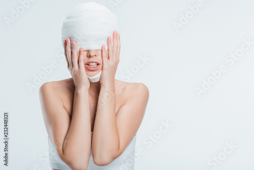 Fotografi woman with bandages touching head after plastic surgery isolated on white