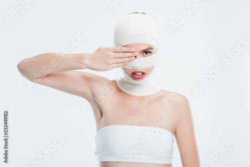 woman with bandages after plastic surgery hiding eye behind hand isolated on whi Fototapeta