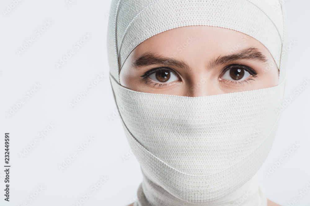 woman with white bandages over face and head looking at camera isolated on white woman with white bandages over face and head looking at camera isolated on white