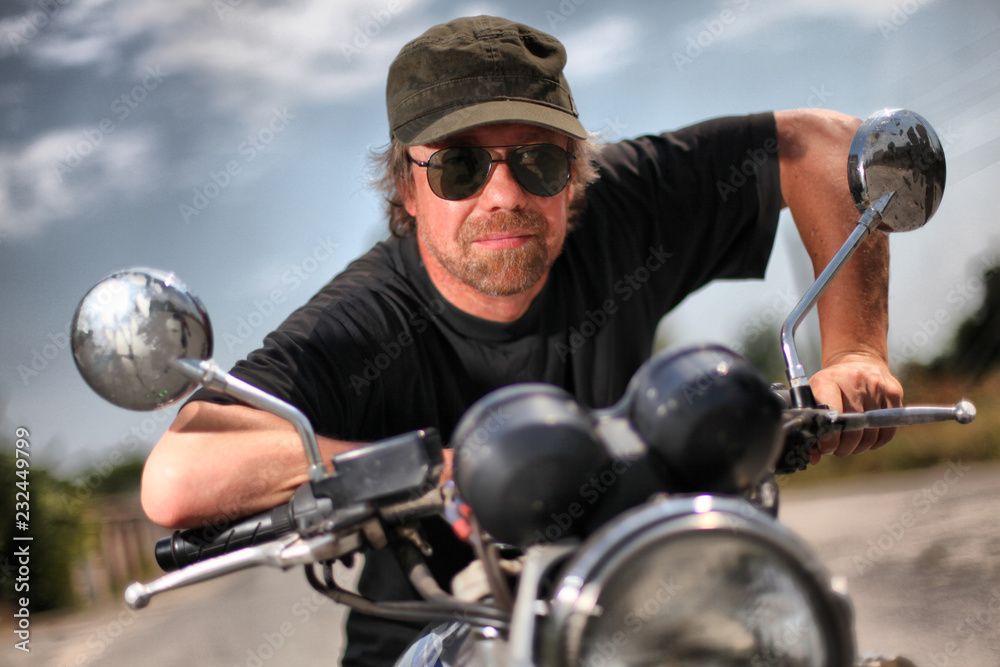 Brutal white man in black glasses on motorcycle.