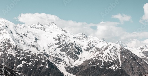 Snowy mountains peaks and light blue sky.