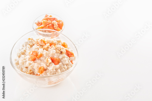 Oatmeal with pumpkin and nuts in a glass plate on a white background. Close-up. Copy space