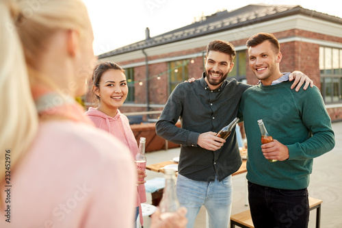 leisure and people concept - happy friends with drinks hugging at rooftop party