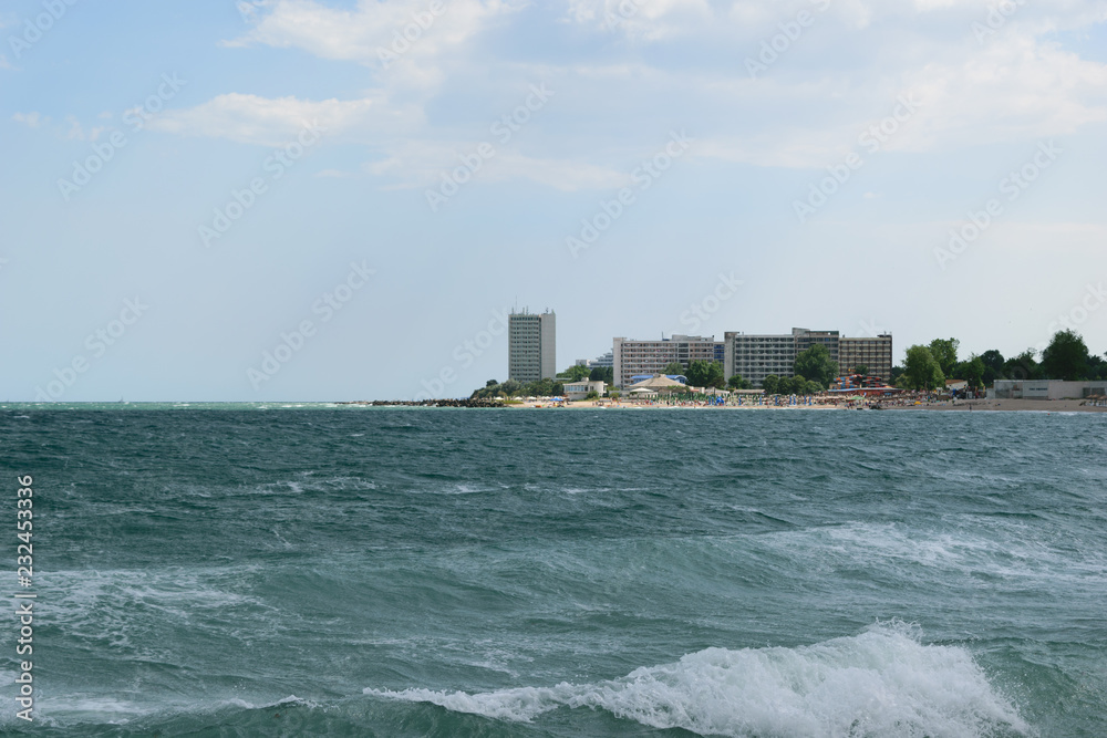 Neptun, Romania - July 8, 2017: The Black Sea changes colour to turquoise due to a natural but very rare phenomenon caused by microorganism. In the background is the beach resort in Neptun, Constanta Neptun, Romania - July 8, 2017: The Black Sea changes colour to turquoise due to a natural but very rare phenomenon caused by microorganism. In the background is the beach resort in Neptun, Constanta