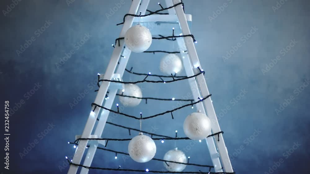 Stepladder decorated with garland, Christmas tree decorations agaist art blue grunge background. New year celebration during repair work or christmas seasonal sale on construction service. Corporate Stepladder decorated with garland, Christmas tree decorations agaist art blue grunge background. New year celebration during repair work or christmas seasonal sale on construction service. Corporate