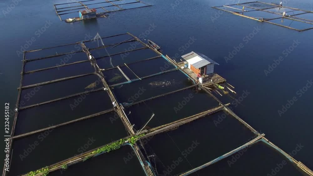 Fish cages and temporary shanty house built at the middle of the mountain lake. Drone aerial